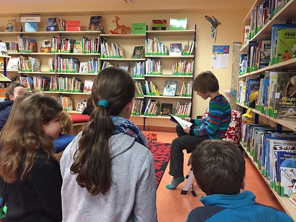 Kinder die einer Vorleserin zuhören.