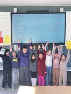 Viele SchülerInnen welche die Hände hochstrecken bei den Juniorwahlen Kids