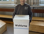 Ein Schüler welcher eine Wahlurne bei den Juniorwahlen Kids hält.
